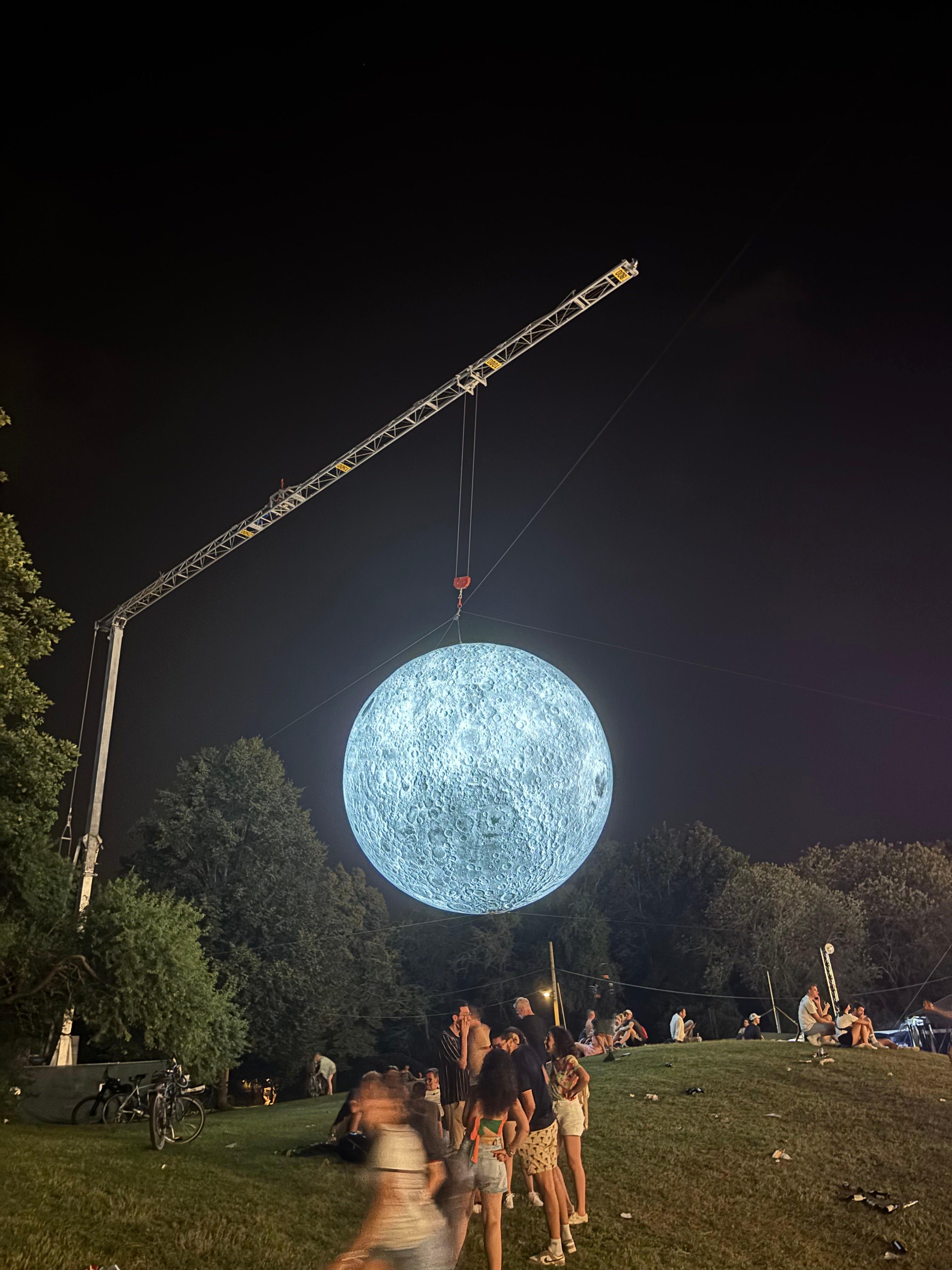 Giant glowing moon art installation in a park at night