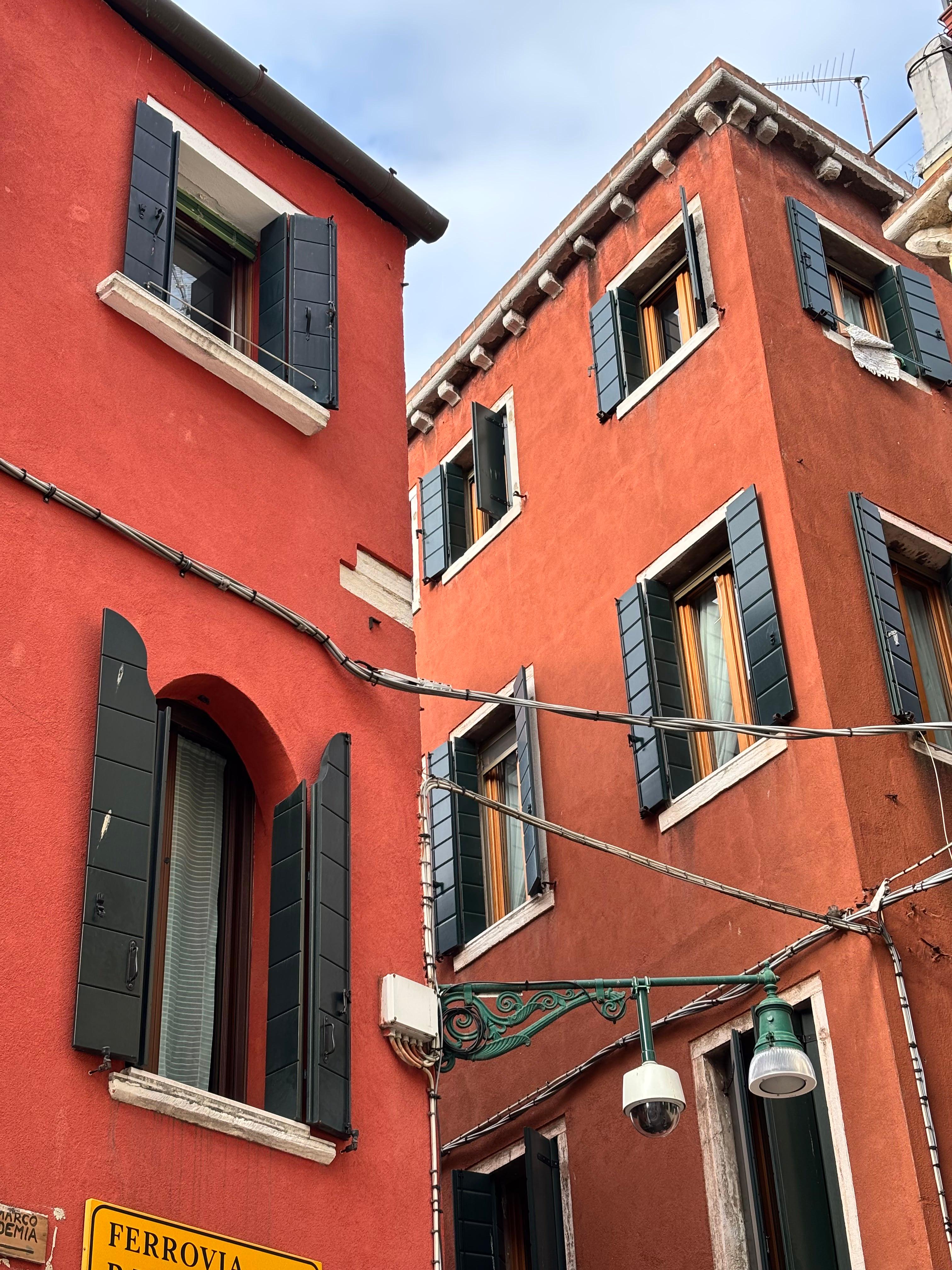 Red Venetian building with shuttered windows near Ferrovia