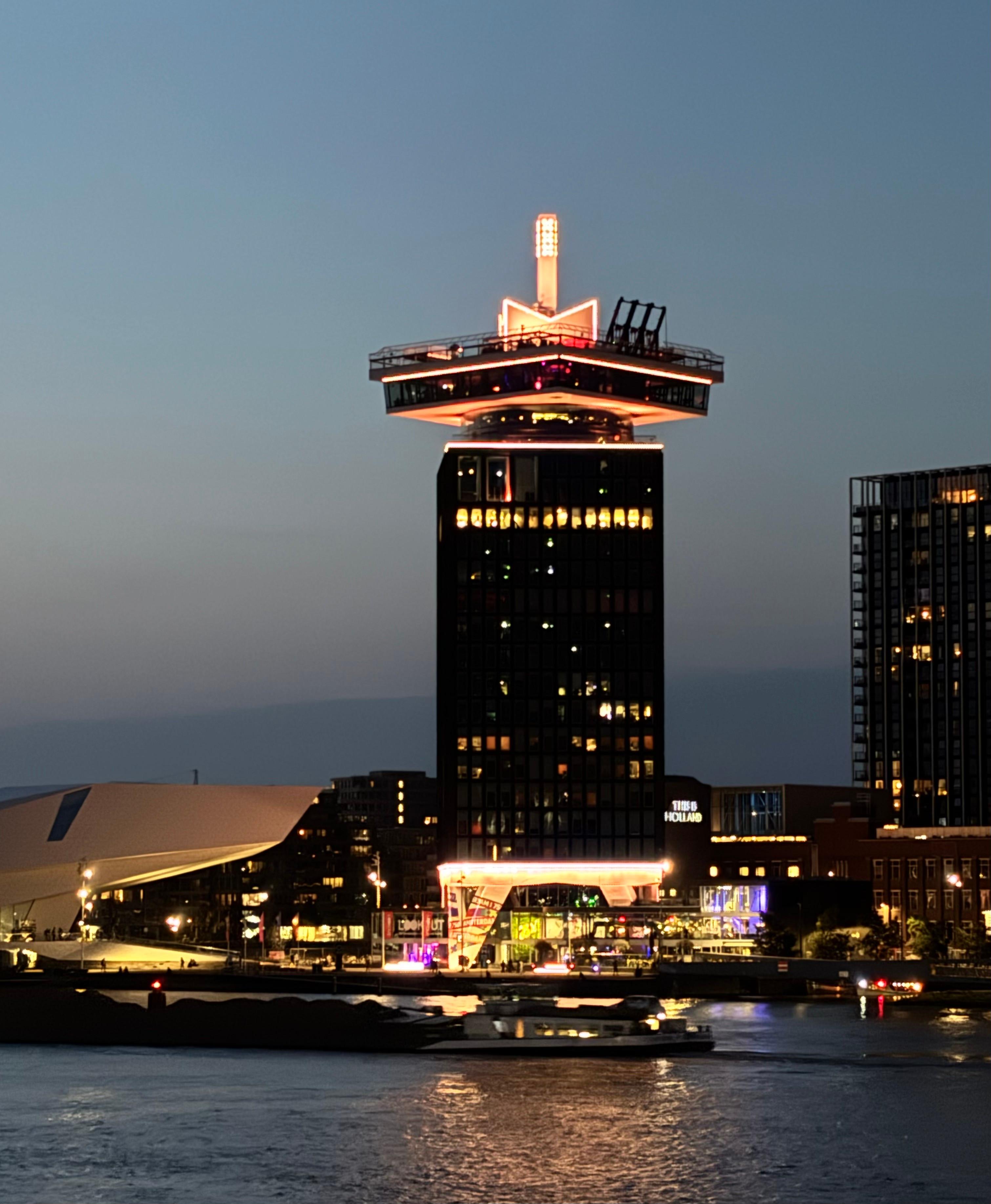 A'DAM Lookout Tower lit up at night across the IJ waterway